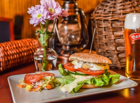 Srbský burger Vojvodina alebo Belgrado s hranolkami a pivom alebo Kofolou.