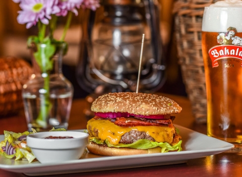 Srbský burger Vojvodina alebo Belgrado s hranolkami a pivom alebo Kofolou.