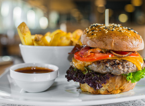 Hovädzí burger v domácej žemli so steakovými hranolkami v bistre na jednotku.